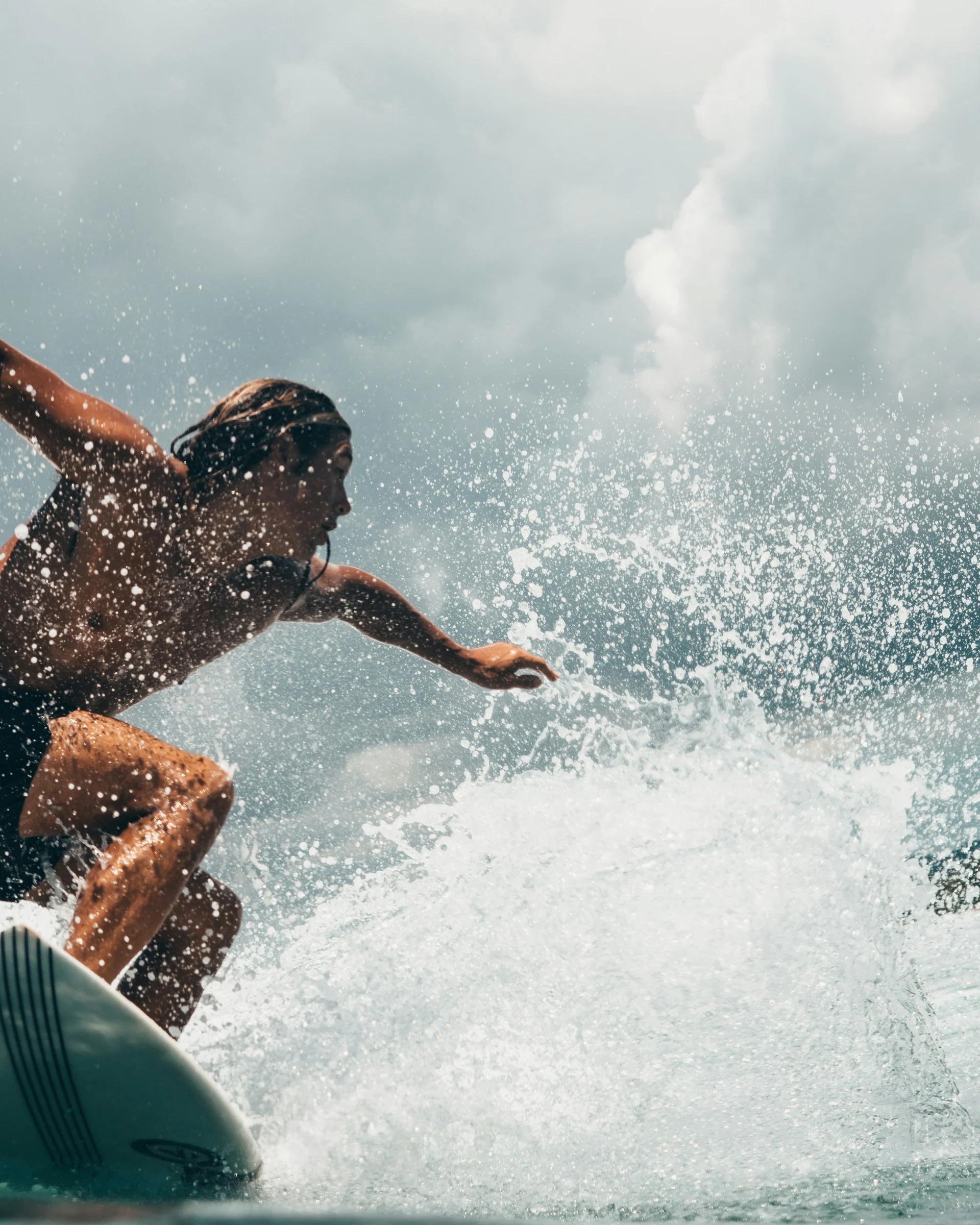 Ein Surfer fährt durch eine Welle, umgeben von spritzendem Wasser.